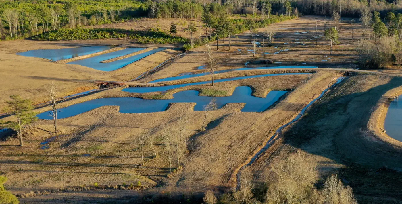 Aerial view of a network of shallow ponds and flooded channels among dry fields and bare trees